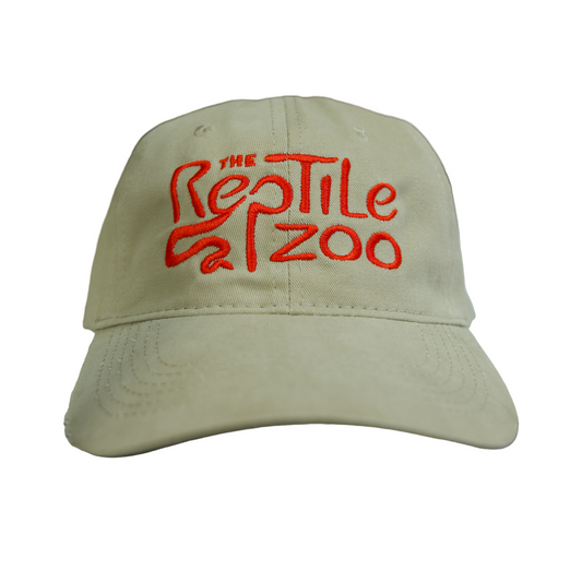 Beige cap with red text 'The Reptile Zoo' on a white surface with a textured green background